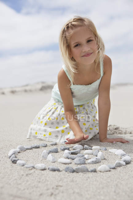 Портрет маленької блондинки, що грає з галькою на пляжі — стокове фото