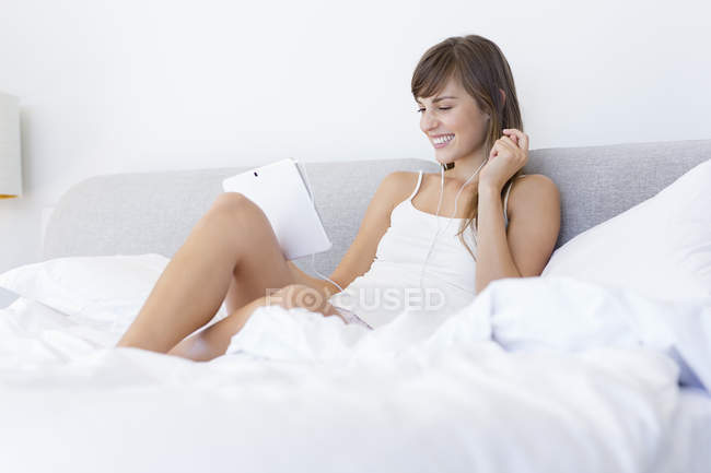 Junge Frau schaut Film auf digitalem Tablet im Bett — Stockfoto