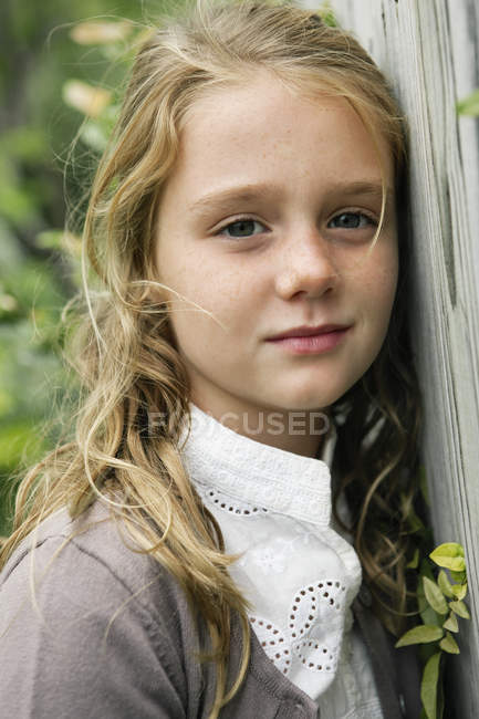 Retrato de menina loira sonhadora inclinando-se na cerca no jardim — Fotografia de Stock