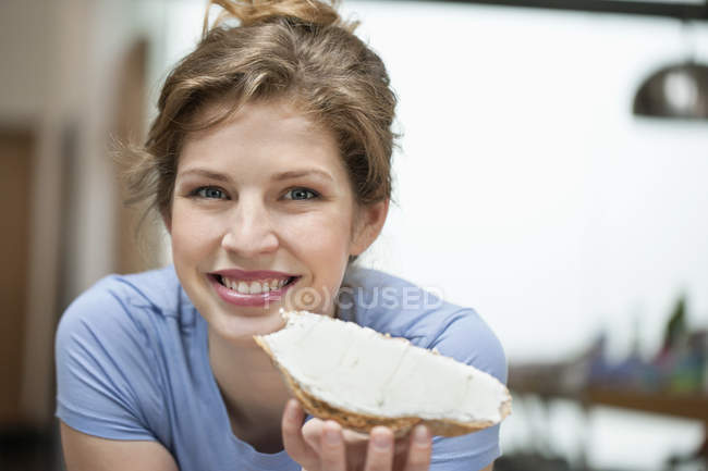 Ritratto di donna sorridente che mangia pane tostato con crema diffusa — Foto stock