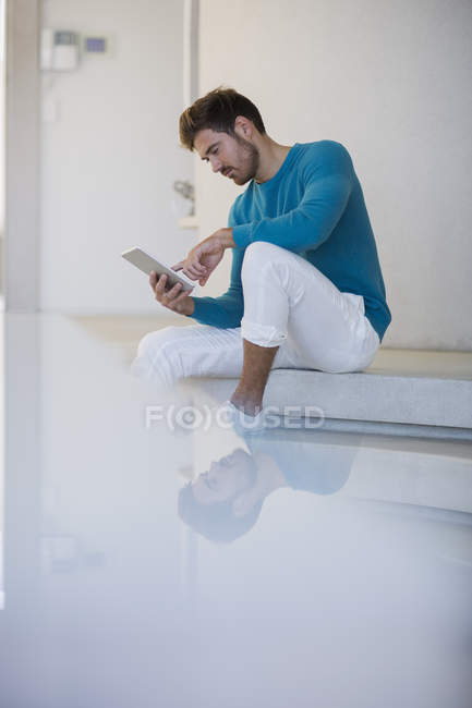 Jovem homem bonito usando tablet digital em escadas brancas — Fotografia de Stock