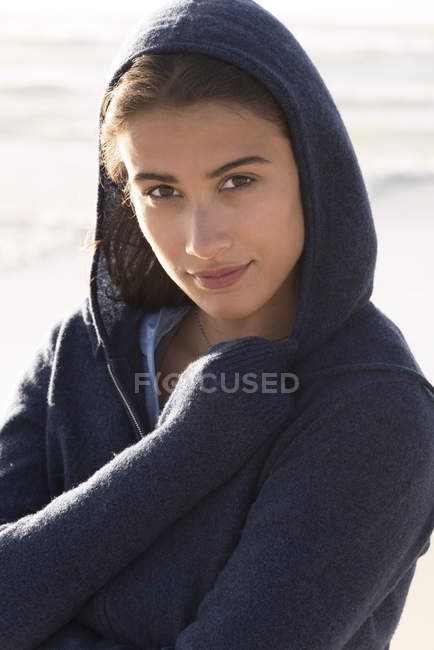 Primer plano de la joven encantadora mujer con capucha en la playa - foto de stock