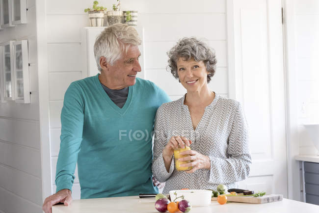 Portrait of happy senior couple preparing food in kitchen — Stock Photo