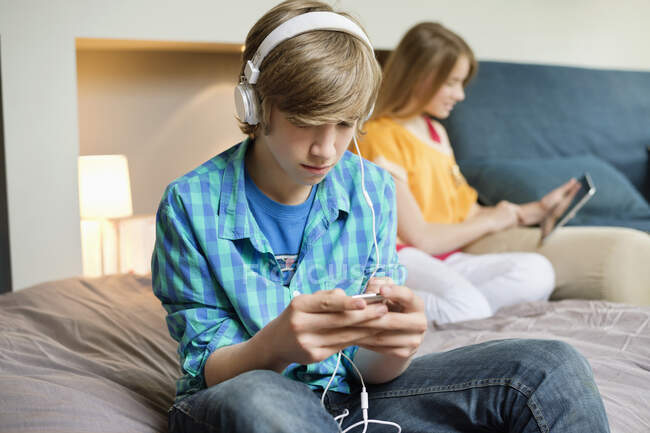 Ragazzo adolescente che ascolta musica su iPod con sua sorella usando tablet digitale — Foto stock