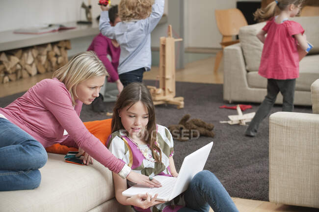 Жінка допомагає доньці використовувати ноутбук — стокове фото