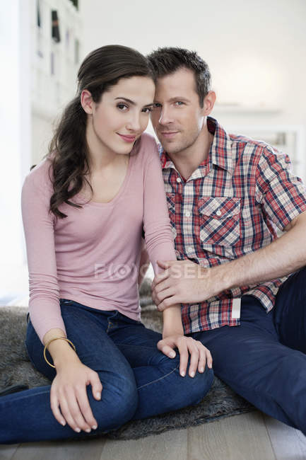 Retrato de pareja romántica sentada en el suelo juntos - foto de stock