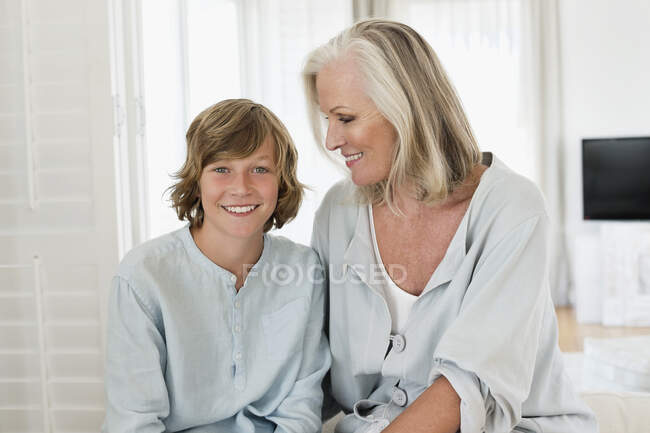 Retrato de un niño sentado con su abuela y sonriendo - foto de stock