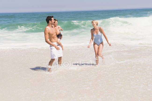 Cheerful family playing on sandy beach — Stock Photo