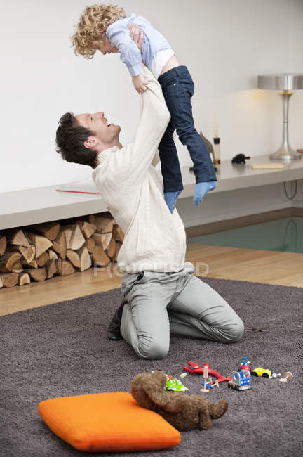 Веселий чоловік грає з сином на килимі вдома — стокове фото
