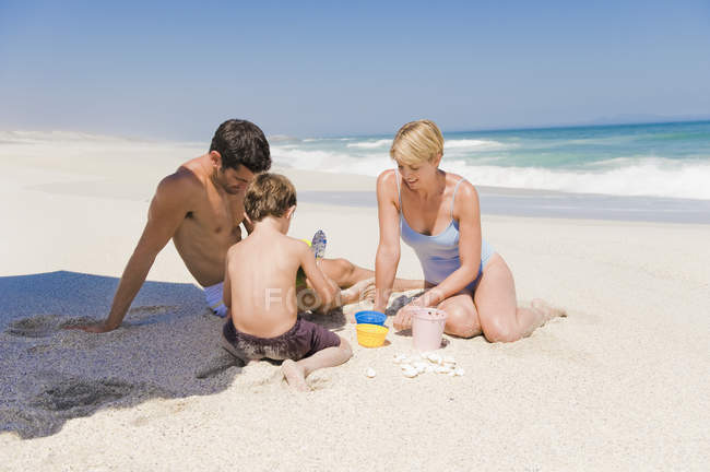 Famiglia che fa castello di sabbia sulla spiaggia — Foto stock
