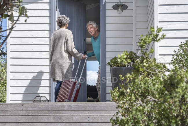 Старший мужчина приветствует женщину в дверях — стоковое фото