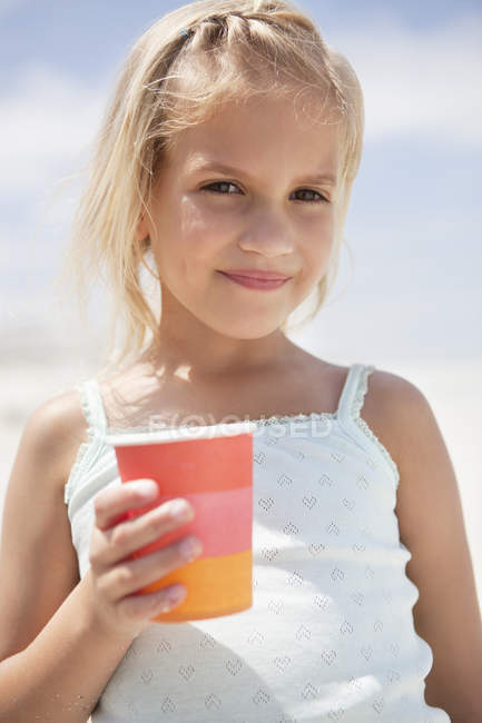 Портрет милой маленькой девочки, держащей стекло на пляже — стоковое фото