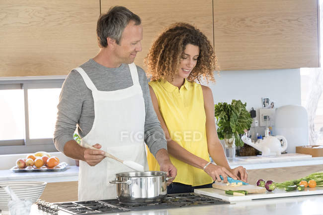 Pareja feliz preparando comida en la cocina juntos - foto de stock