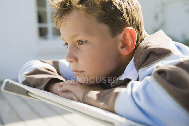 Крупним планом нудний хлопчик відпочиває на стільці палуби — стокове фото