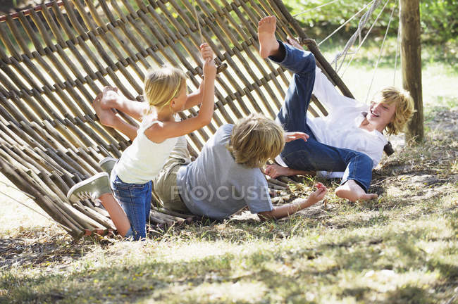 Crianças caindo da rede no jardim de verão — Fotografia de Stock