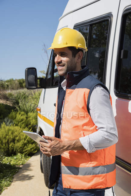 Sorridente engenheiro masculino com tablet digital em pé na van — Fotografia de Stock
