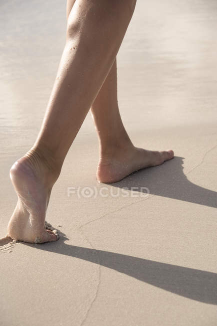 Slim legs of woman walking sandy on beach — Stock Photo