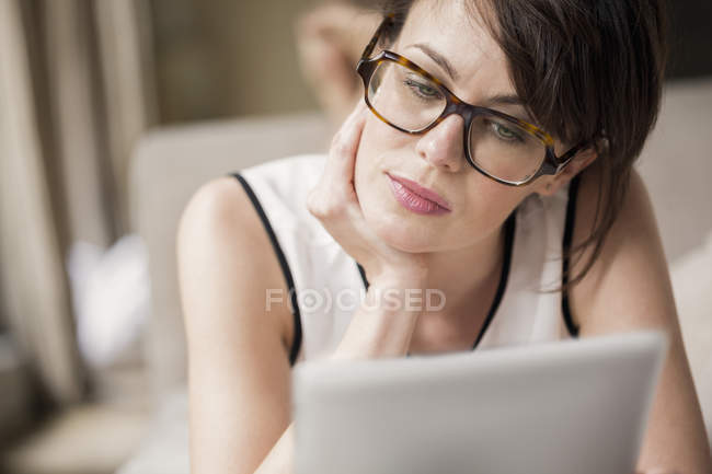 Frau liegt auf Bett und nutzt digitales Tablet — Stockfoto
