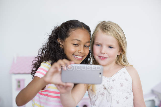 Smiling little girls taking selfie with camera phone — Stock Photo