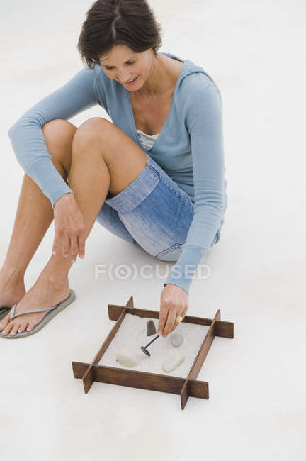 Усміхнена жінка грає з пісочницею на підлозі — стокове фото