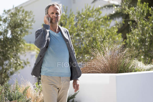 Homem maduro falando no telefone celular em um jardim — Fotografia de Stock