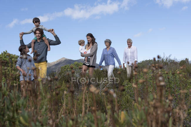 Heureuse famille multi-génération marchant sur le paysage — Photo de stock