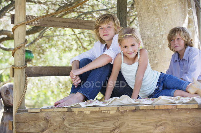 Ritratto di bambini seduti nella casa sull'albero nel giardino estivo — Foto stock
