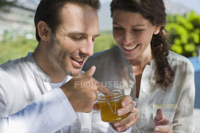 Man holding a jar of marmalade with woman smiling in garden — Stock Photo