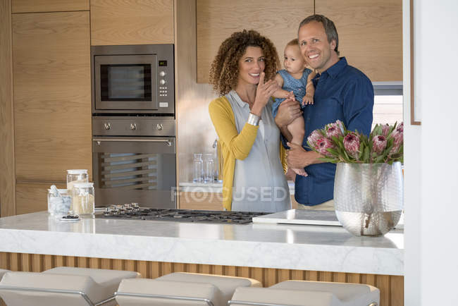 Счастливая пара, стоящая на кухне с маленькой дочерью — стоковое фото