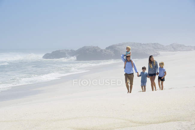 Счастливая семья с детьми, гуляющими на пляже — стоковое фото