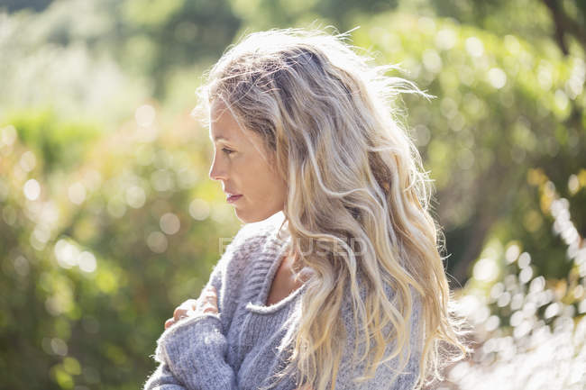 Жінка в затишному светрі, що стоїть в саду — стокове фото