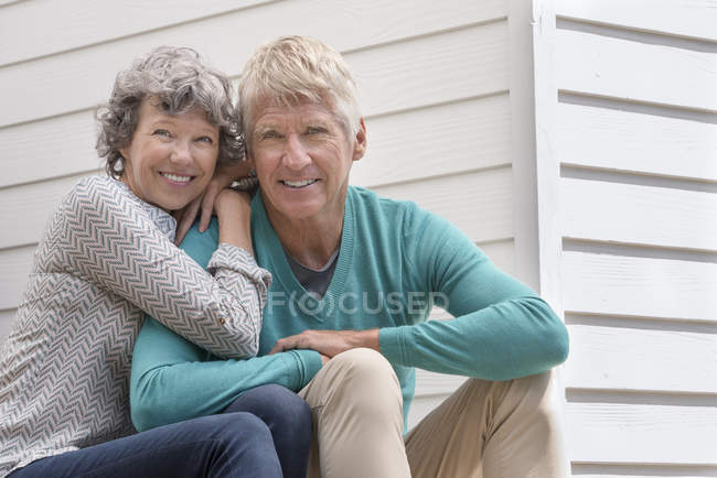 Portrait of happy senior couple sitting outside of house — Stock Photo