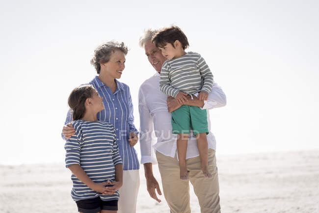 Glückliche Großeltern mit Enkeln am Strand — Stockfoto