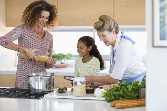 Mulher sênior com filha e neta preparando comida na cozinha — Fotografia de Stock