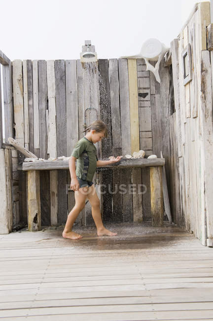 Маленький хлопчик стоїть під пляжним душем влітку — стокове фото