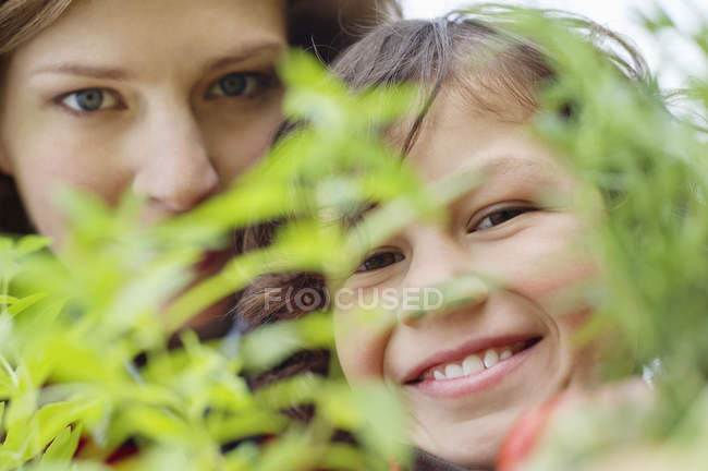 Портрет усміхненого хлопчика з матір'ю, що дивиться на рослину — стокове фото
