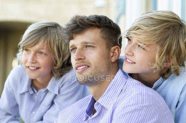Un homme souriant et des enfants regardant ailleurs ensemble — Photo de stock
