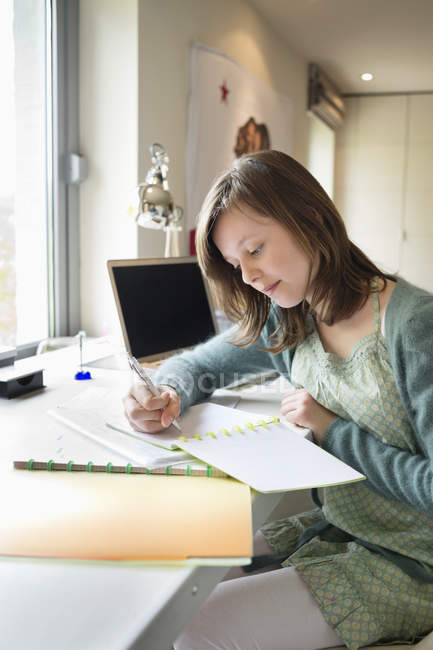 Adolescente enfocada estudiando en el escritorio en casa - foto de stock