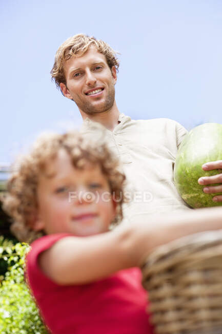 Pai e filho segurando frutas — Fotografia de Stock