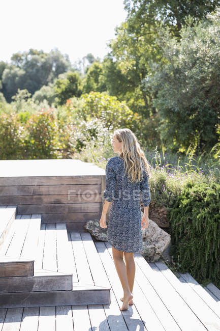 Donna bionda in abito godendo in scale di legno in giardino — Foto stock