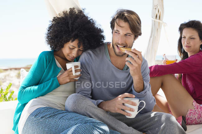 Couple prenant un café avec leur ami en arrière-plan — Photo de stock