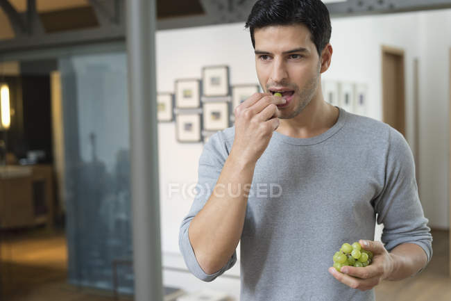 Чоловік їсть зелений виноград вдома — стокове фото