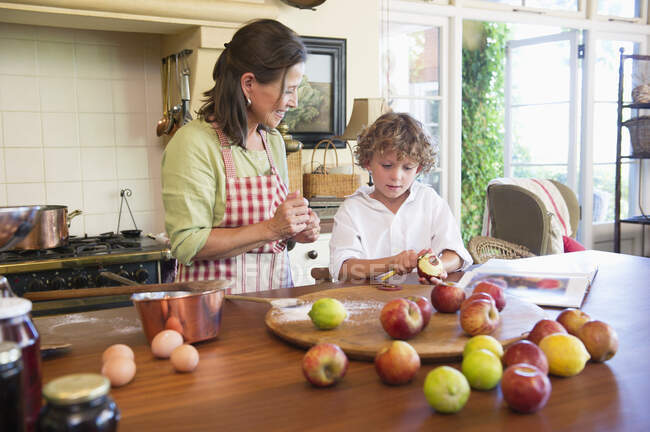 Großmutter und kleiner Junge schälen zu Hause einen Apfel — Stockfoto