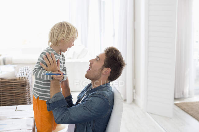 Jovem brincando com seu filho em casa — Fotografia de Stock