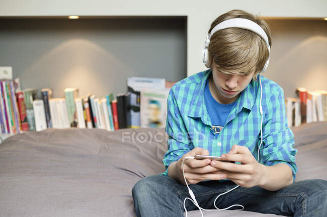 Мальчик-подросток слушает музыку на iPod дома — стоковое фото