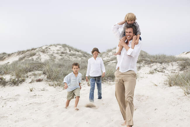 Mann läuft mit Kindern auf Sand — Stockfoto