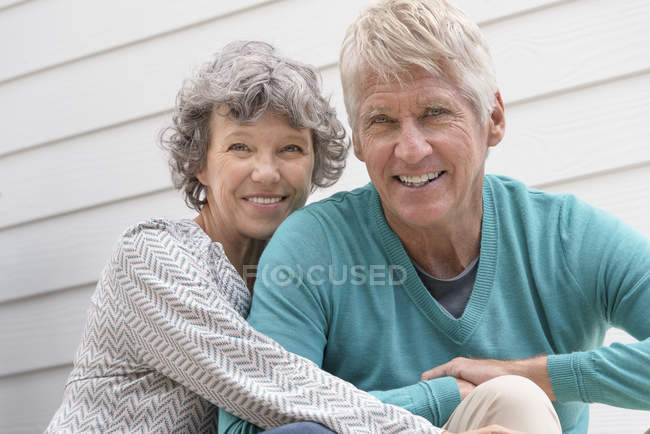 Retrato de feliz pareja de ancianos sentados fuera de casa - foto de stock