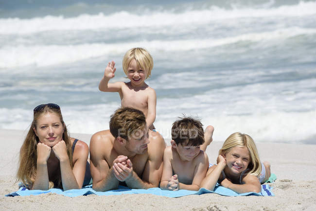 Retrato de familia feliz relajada acostada en la playa - foto de stock