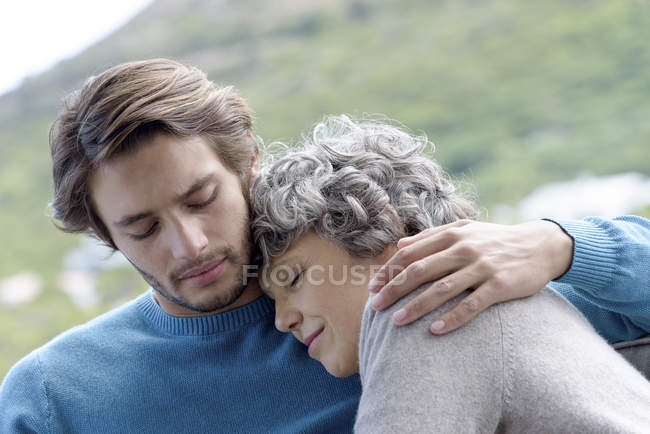 Любящий сын обнимает мать на открытом воздухе — стоковое фото