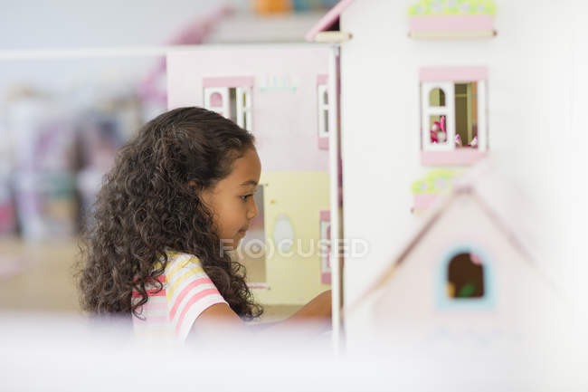 Kleines Mädchen spielt mit Puppenhaus im Zimmer — Stockfoto